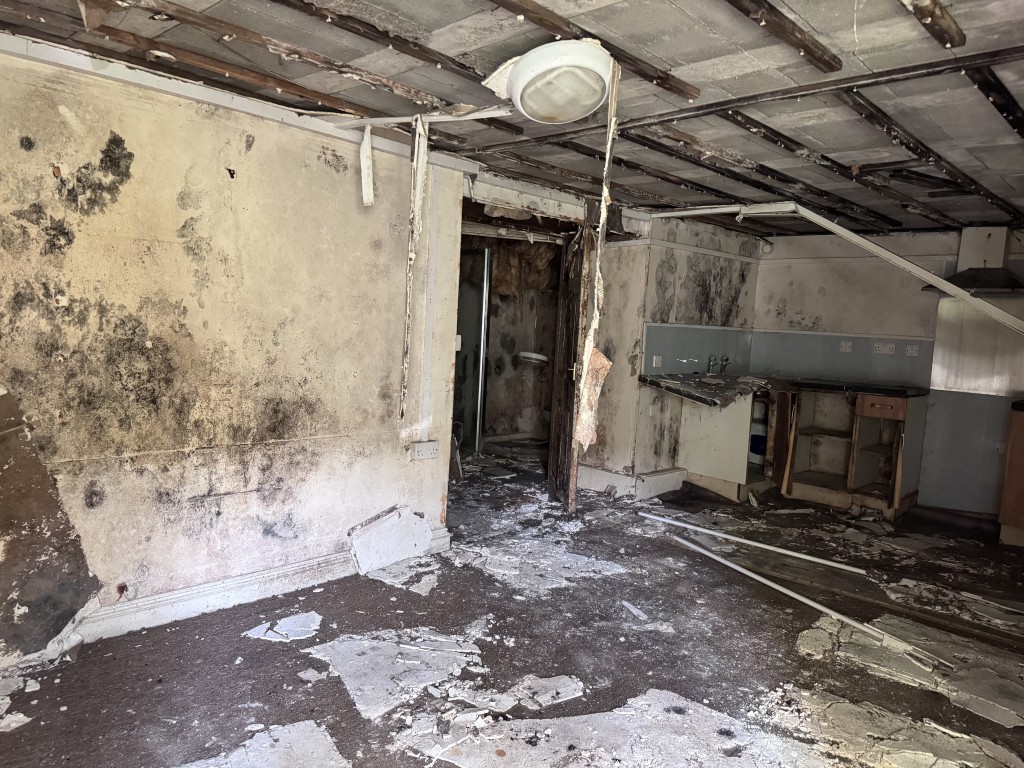 Lot: 9 - TOWN CENTRE BUILDING ARRANGED AS THIRTEEN FLATS IN NEED OF SIGNIFICANT IMPROVEMENT - Kitchen/living in a poor condition flat